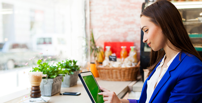 Two women shopping online for clothes using a laptop, with one pointing at the screen and the other holding a credit card.